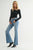 Woman wearing a black top and blue flared jeans on a white background