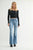 Woman wearing a black long-sleeve top and blue jeans on a white background