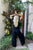 Person in black outfit standing in a garden with plants and a door in the background